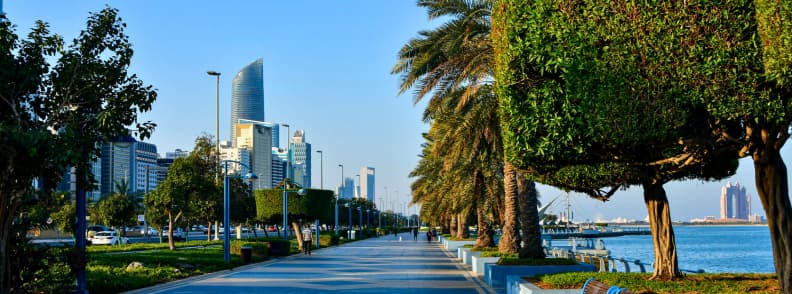 Free things to do in Abu Dhabi Corniche promenade Abu Dhabi Corniche promenade with palm trees and modern skyscrapers along the waterfront