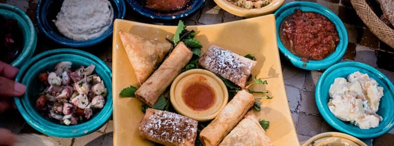 Assorted traditional Emirati dishes served in colorful bowls with pastries and dips in Abu Dhabi restaurant