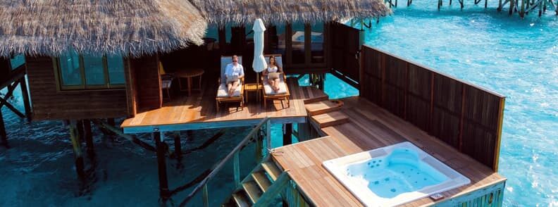 Couple of digital nomads working from an overwater bungalow in the Maldives