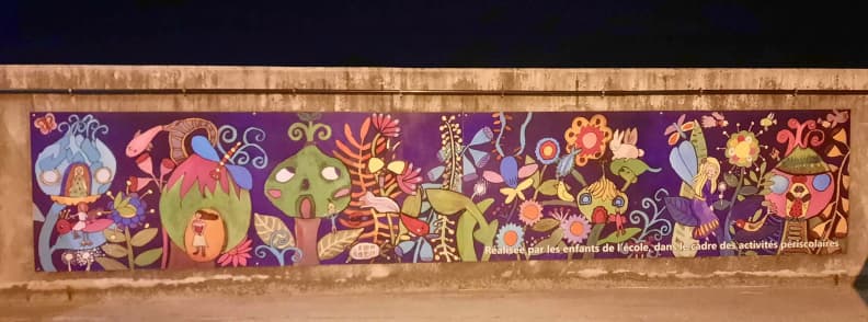 Bagnols en Foret Schoolchildren Colorful Village Mural Colorful mural created by schoolchildren in Bagnols-en-Forêt, featuring imaginary houses, trees, flowers, and woodland creatures, displayed near the top of Parking du Château.