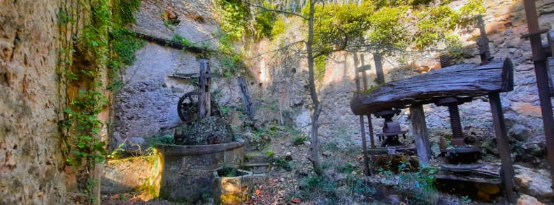 Old Water Mill Ruins Bagnols en Foret Vauloube Valley Abandoned water mill in the Vauloube valley near Bagnols-en-Forêt, with old wooden machinery, a stone basin, ivy-covered walls, and trees growing among the ruins.