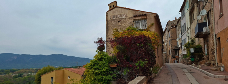 Rue de l Ancienne Mairie Former Hotel Miresterel Bagnols Rue de l’Ancienne Mairie in Bagnols-en-Forêt, showing the former Hôtel Miresterel with its faded painted sign, autumn-colored climbing vines, old stone houses, and distant hills.