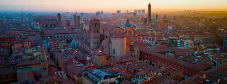 Sunset aerial view of Bologna with San Petronio Basilica and Asinelli Tower, showcasing Bologna hidden gems, best local restaurants, and historic landmarks