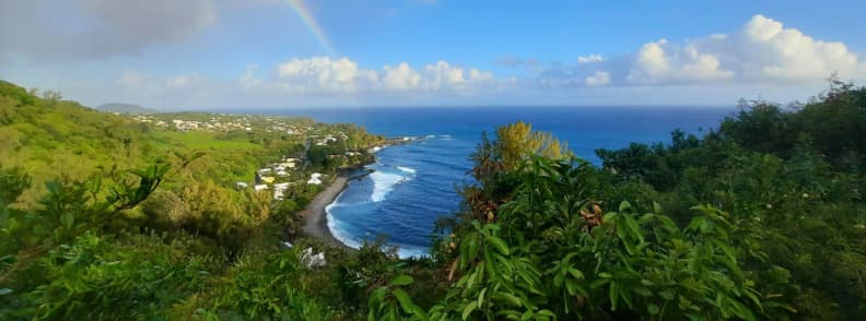 Scenic coastal view of La Réunion near Saint-Philippe with rainbow, ideal for first-time visitors to La Réunion, featuring black sand beaches and lush coastline