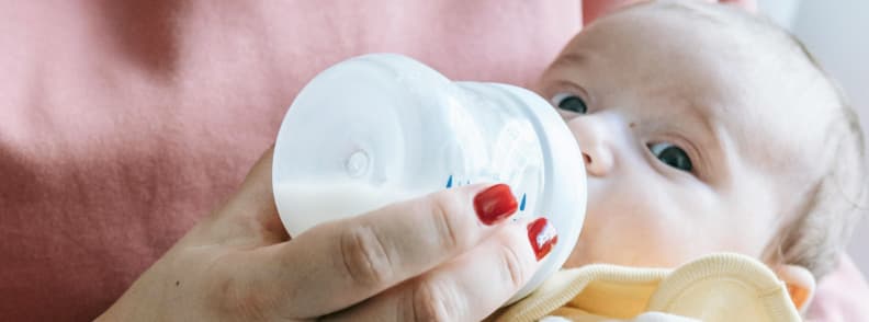 Bottle Feeding While Traveling With a Baby Parent feeding infant with bottle during traveling with a baby, showing milk, calm setup, and infant focus