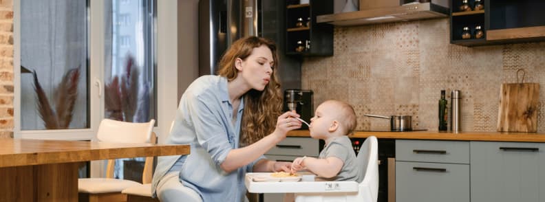 Feeding Baby at the Accommodation Travel Friendly Mealtime Routine Mother feeding baby in high chair at vacation rental, showing practical meals while traveling with a baby