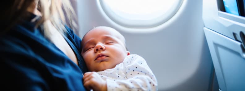 Flying with a Baby Nap Time on a Plane Baby sleeping on mother’s chest during flight. A peaceful moment while traveling with a baby and using a lap infant ticket