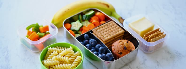 Healthy toddler snacks and meals packed for air travel A colorful assortment of toddler snacks including fruits, veggies, crackers, cheese, pasta, and a muffin, illustrating practical snack and meal strategies for flying with toddlers