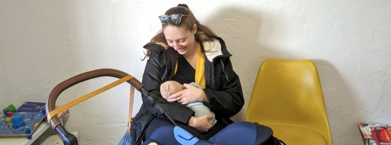 Mirela Letailleur Breastfeeding While Traveling With a Baby Real Life On the Go Mirela Letailleur The Travel Bunny, breastfeeding her baby during a travel stop, showing real moments of traveling with a baby
