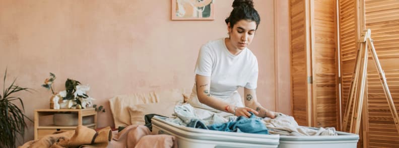 Packing for a Trip Baby Travel Checklist Essentials Mother packing clothes and baby travel gear in suitcase while preparing for traveling with a baby