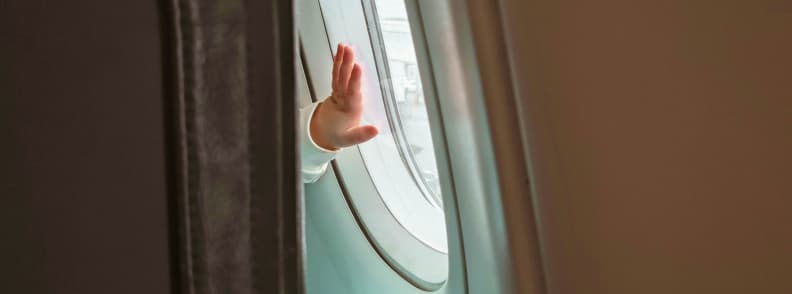 Toddler hand on airplane window symbolising in flight comfort and health for young travelers Small toddler hand touching airplane window during flight, capturing a quiet moment focused on in-flight comfort and health for toddlers