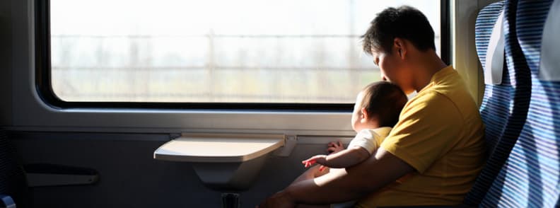 Train Travel With Baby Scenic Ride With Comfort and Calm Parent and baby seated by a train window, bonding peacefully while traveling with a baby on a long-distance journey