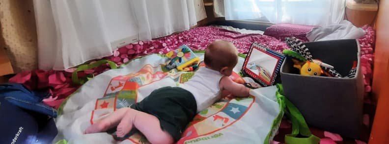 Tummy Time in the Camper RV Travel Baby Moments Baby doing tummy time on playmat in camper while traveling with a baby, surrounded by toys and soft light