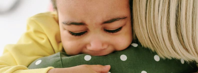 dealing with toddler tantrums plane Upset toddler crying in caregiver’s arms, a real moment that captures the challenge of dealing with toddler tantrums on a plane while flying with young children