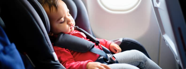 toddler flight tips car seat A toddler sleeping comfortably in a car seat on an airplane, showing safe travel setup and real-life application of toddler flight tips for flying with toddlers