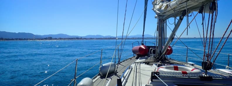 Mediterranean sailing itinerary including Pisa Forward-facing view from a sailboat on a Mediterranean sailing itinerary including Pisa, approaching the Tuscan coast under calm conditions with land visible ahead.