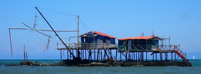 Retoni history Arno River fishing traditions and culture Two traditional Retoni fishing huts on stilts over the Arno River estuary, representing Arno River fishing traditions and culture near Marina di Pisa, part of the traditional Italian fishing heritage along the Tuscan coast sailing route.