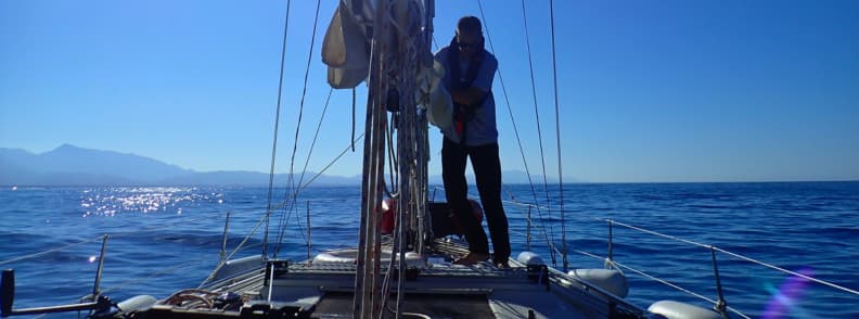 mathieu letailleur sailboat puzzle sailing budget Italy Sailor Mathieu Letailleur on deck preparing lines during a calm sailing Tuscany day on the Ligurian Sea, illustrating hands-on crew work and real conditions for a sailing budget Italy trip.
