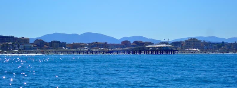 sailing Ligurian Sea Viareggio Italy Coastal view of Viareggio in Italy from the sea during sailing Ligurian Sea, showing the long pier and beachfront skyline with Tuscan mountains in the background.