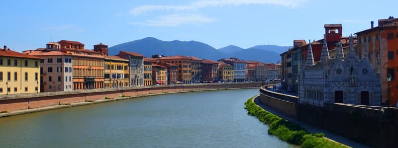 View of Pisa by boat along the Arno River, showing colorful riverside buildings and the Church of Santa Maria della Spina, part of the route when sailing up the Arno River to Pisa.