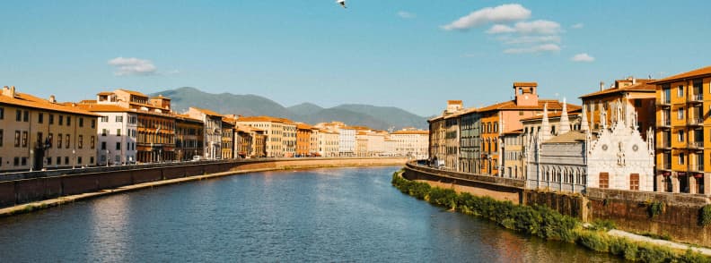 santa maria della spina river arno pisa View of Santa Maria della Spina and the River Arno in Pisa, Italy, with colorful historic buildings and distant mountains under a blue sky