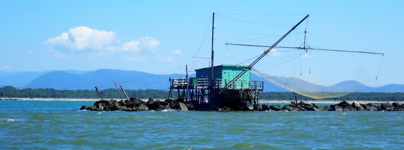 traditional Italian fishing Retoni history Traditional wooden Retoni fishing hut on stilts at Bocca d’Arno, Italy, seen while entering the Arno River navigation route toward Pisa by sailboat.
