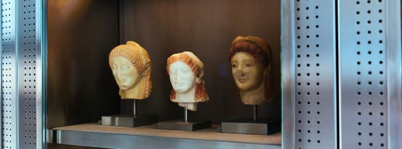Marble heads of Archaic period statues displayed at the Acropolis Museum in Athens, showcasing ancient Greek art and artifacts