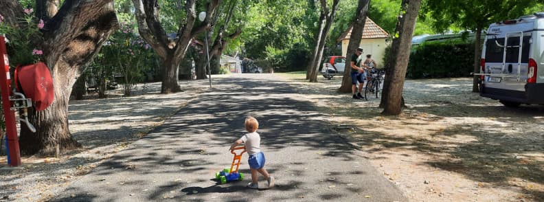 Family Friendly Camping Fouguieres in Carces Toddler playing with a toy lawn mower along the tree-lined lane at Camping Fouguières in Carcès