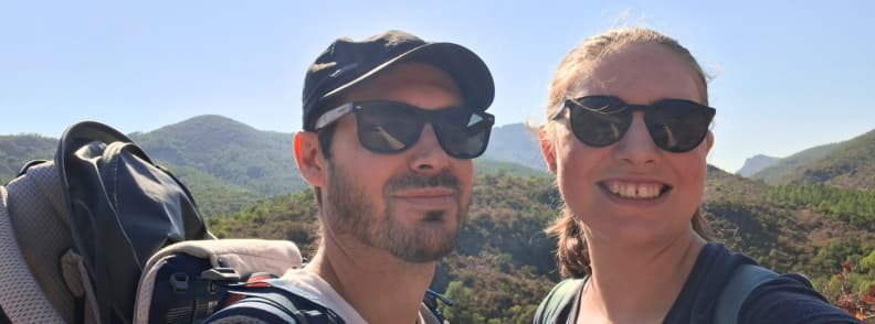 Local insider tips hikers Mathieu and Mirela Letailleur Esterel Massif Saint Raphael Mathieu and Mirela Letailleur The Travel Bunny, two hikers in sunglasses taking a selfie on the Estérel Massif trail near Col d’Aubert with a baby carrier and pine covered hills above Saint-Raphaël