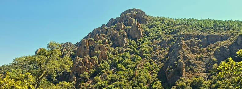 Red porphyry cliffs Ravin du Gratadis Esterel Massif Craggy red porphyry cliffs rising above pine covered slopes in the Estérel Massif near Saint-Raphaël viewed from the Ravin du Gratadis trail