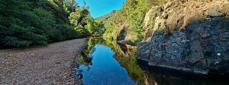 Reflective stream pool Ravin du Gratadis Esterel Massif Saint Raphael Calm reflective stream pool in the Ravin du Gratadis with a red rock wall on one side and forest on the other in the Estérel Massif near Saint Raphaël