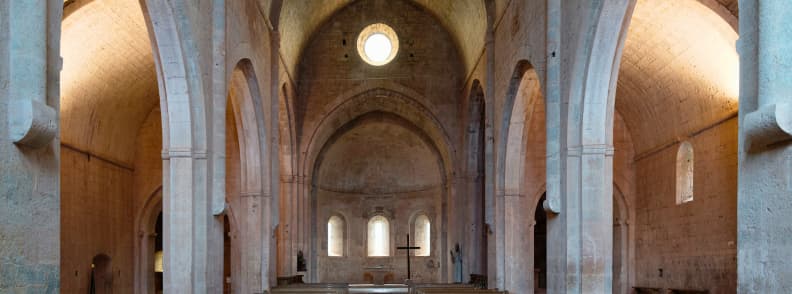 Romanesque Nave of Abbaye du Thoronet Historic Monastery Provence Central nave of Abbaye du Thoronet in Provence with high vaulted arches, round clerestory window, and simple stone altar