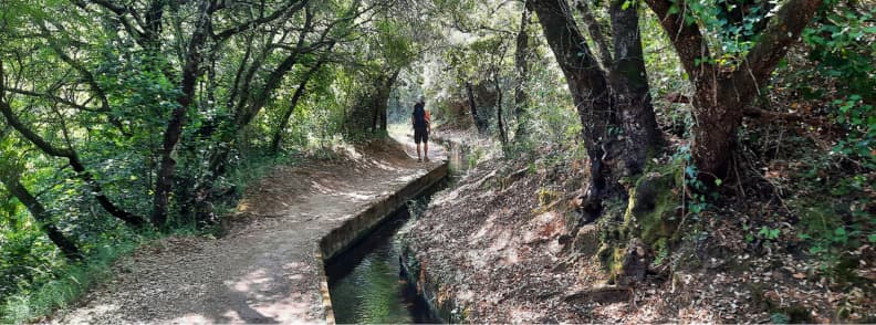 Shaded Canal Path on the Hike to Cascades de Caramy from Carces Man carrying a toddler in a hiking carrier on a shaded trail along the irrigation canal to Cascades de Caramy in Carcès