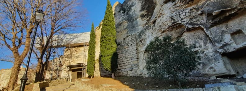 Stone entrance of the Porte d’Eyguières at Les Baux-de-Provence with trees and rock walls in the medieval village