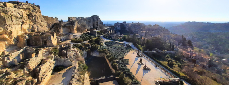 Panoramic view of Château des Baux-de-Provence ruins with trebuchet and medieval fortress walls overlooking the Alpilles