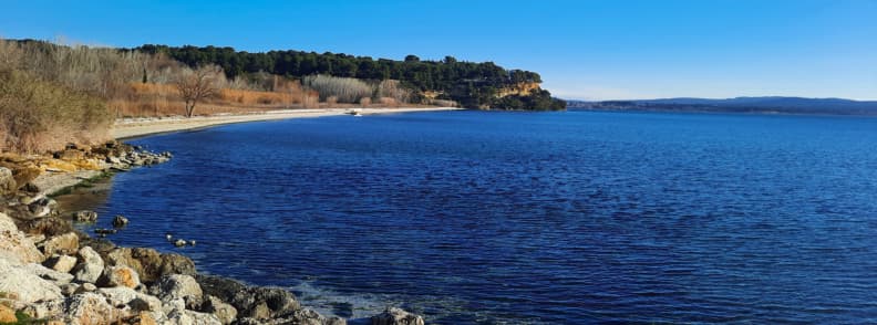 Etang de Berre Istres lagoon Provence travel guide Calm blue waters of the Étang de Berre near Istres and
Camping Le Vallon Des Cigales, with rocky shores, pine-covered cliffs, and clear winter skies in southern France.