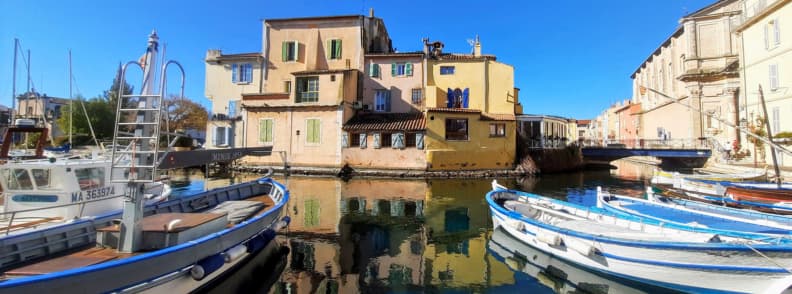Martigues Miroir aux Oiseaux canal reflections Provence Fishing boats moored along the colorful canal houses of Martigues’ Miroir aux Oiseaux, with reflections shimmering under the Provençal sun.