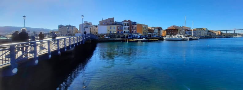 Martigues blue bridge canal Etang de Berre Provence Blue pedestrian bridge in Martigues crossing the canal toward colorful waterfront buildings and boats under clear Provençal skies.