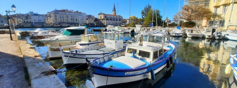 Martigues fishing boats canal Eglise Saint Genest Provence Fishing boats moored in the canal of Martigues with the Église Saint-Genest visible in the background under clear Provençal skies.