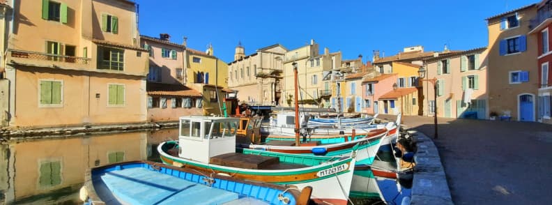 Miroir aux Oiseaux Martigues Eglise Sainte Marie Madeleine Provence Traditional fishing boats moored at the Miroir aux Oiseaux in Martigues with the Église Sainte-Marie-Madeleine and the nearby bridge reflected in the calm canal water.
