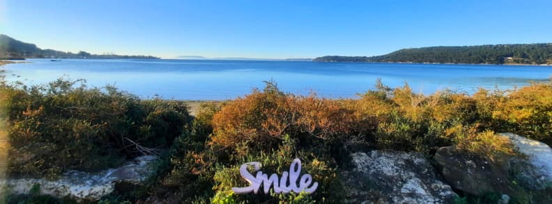 Morning view Etang de Berre Saint Chamas Provence travel Morning view over the Étang de Berre from the lakeshore in Saint-Chamas, with calm blue water, low sunlight, and bushes framing the scene near a camper parking spot.