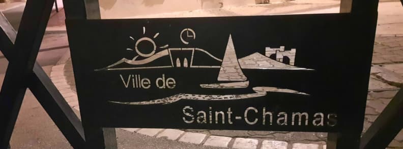 Saint Chamas Provence travel guide Etang de Berre village Metal sign reading “Ville de Saint-Chamas” with engraved symbols of a bridge, sailboat, and hills, marking the entrance to the historic town near the Étang de Berre in Provence.