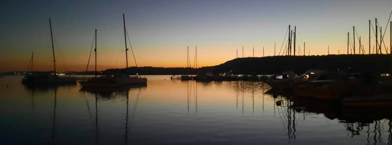 Saint Chamas port sunset Etang de Berre sailing Provence Sailboats moored at the Saint-Chamas port on the Étang de Berre at sunset, their masts reflecting on the calm water under a golden Provençal sky.