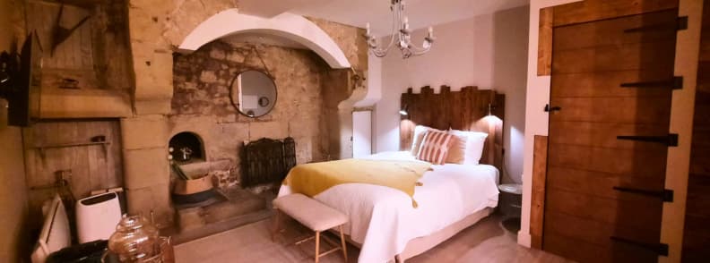 La Chaumiere BedinShop Romans sur Isere bedroom historic charm cozy bedroom inside La Chaumiere BedinShop apartment in Romans sur Isere with stone fireplace and rustic wooden decor