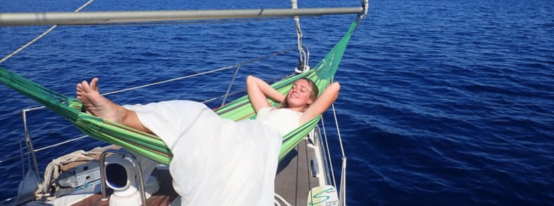 Mirela Letailleur from The Travel Bunny relaxing in a hammock on her sailboat during a slow travel journey across the Mediterranean Sea.
