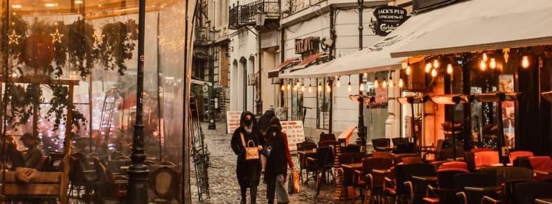 People walking through Bucharest Old Town on a winter morning with cafes and warm lights along the street.
