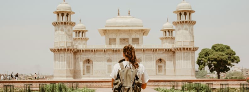 International travel insurance India departure checklist Traveler with backpack facing a historic monument in India before an international trip