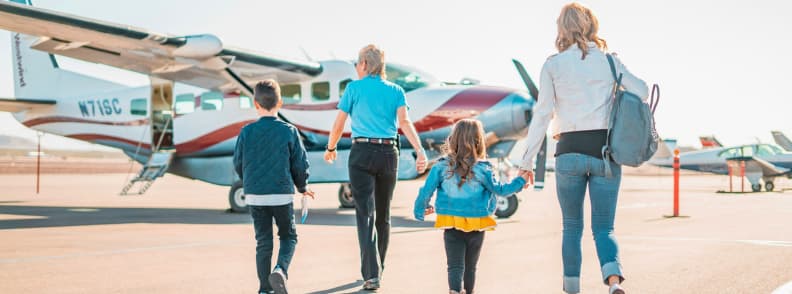 Luxury international travel insurance matters for this family walking toward a small private aircraft during an international trip with luggage and carry on bags
