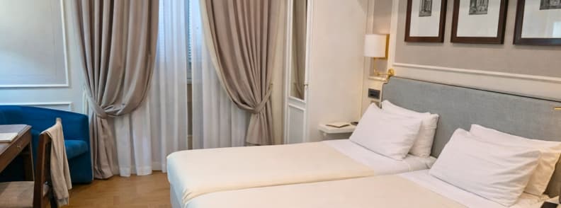 Elegant budget twin room in central Rome with soft lighting and classic decor