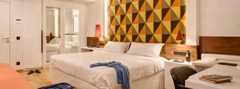 Stylish Rome hotel room with king bed, geometric accent wall, and modern furnishings